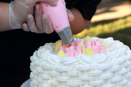 Person decorating a cake with a cream in a pastry shopの写真素材
