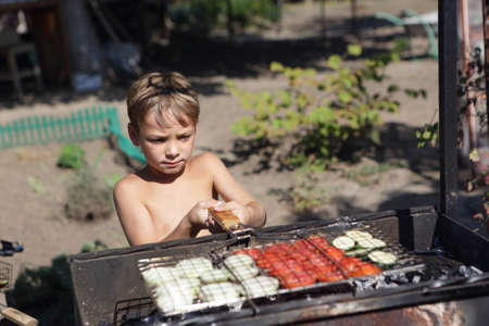 Child is cooking vegetables on the grill