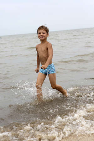 Boy running along the beach in summerの写真素材