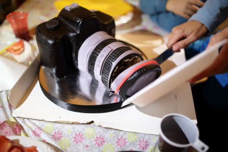 Woman cutting cake in form of cameraの写真素材