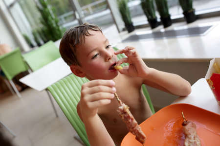 Child eating french fries with kebab in aquaparkの写真素材