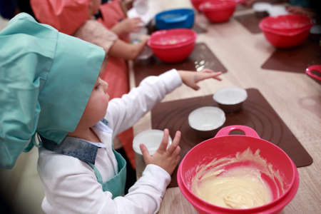 Little cook prepares dough for cupcakes in the kitchen