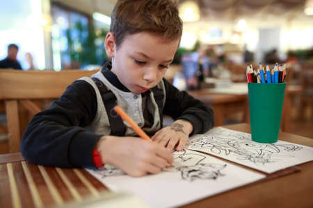 Child drawing at table in a cafeの写真素材