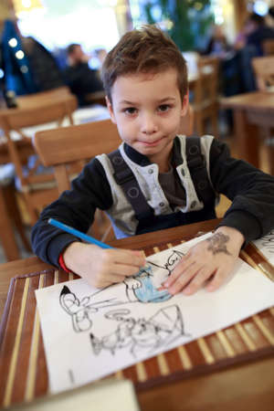 Boy drawing with pencil in a cafeの写真素材
