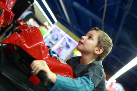 Boy playing in motorcycle simulator at indoor playgroundの写真素材