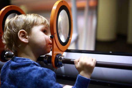 Preschooler looking through magnifying glass system at playgroundの写真素材
