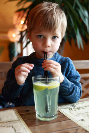 Boy drinking lemonade at table in cafeの写真素材
