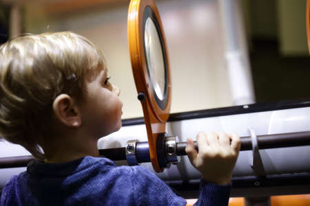 Boy looking through magnifying glass system at playgroundの写真素材