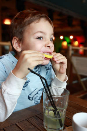 Child drinking lemonade at table in cafeの写真素材