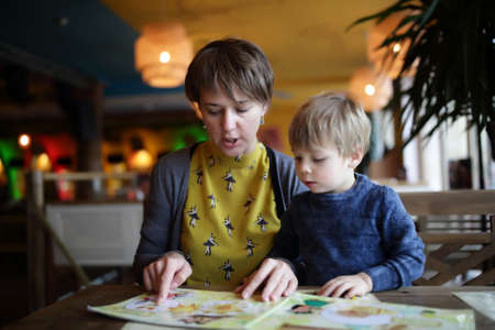 Mother with her son choosing dishes at table in the restaurantの写真素材