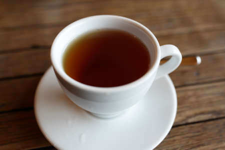 White cup with black of tea on wooden tableの写真素材