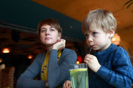 Child has lemonade at table in a restaurantの写真素材