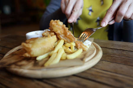 Person eating fillet of cod in restaurantの写真素材