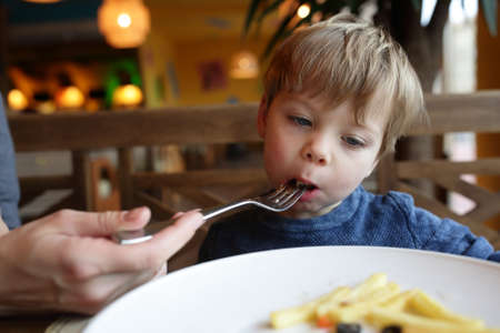 Mother feeding her son in a restaurantの写真素材