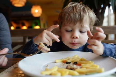 Child eating french fries in a restaurantの写真素材