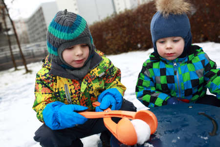 Brothers playing with snowball maker at playgroundの写真素材