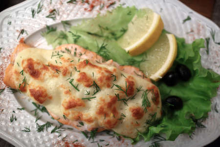 Baked salmon steak with suluguni cheese on plateの写真素材