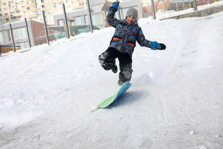 Boy sliding down snow hill in winterの写真素材