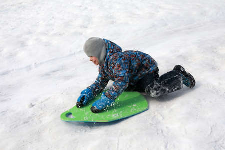Boy rides sledding down from hill in winter