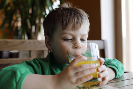 Boy drinking orange juice in a cafeの写真素材