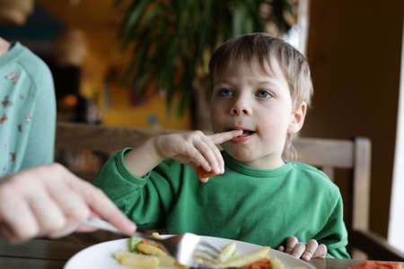 Kid eating french fries in a cafeの写真素材