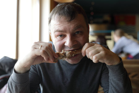 Man eating chicken leg in a restaurant