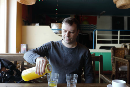 Man pouring orange juice in a cafeの写真素材