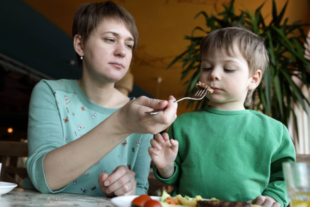Mother feeding her son with a cutletの写真素材