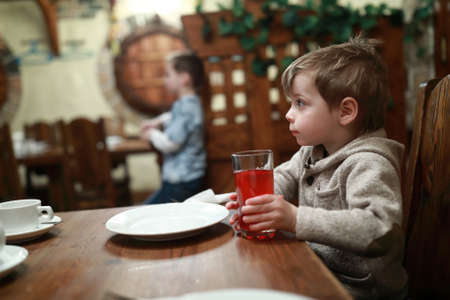 Child has juice at table in cafeの写真素材