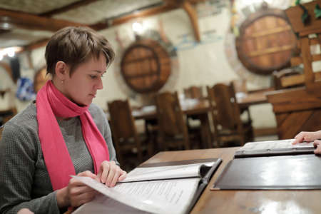 Woman choosing dishes at table in restaurant