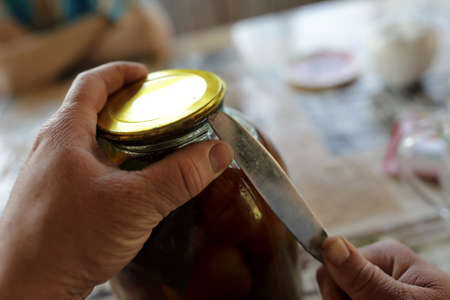 Person opening jar with pickled tomatoes at homeの写真素材