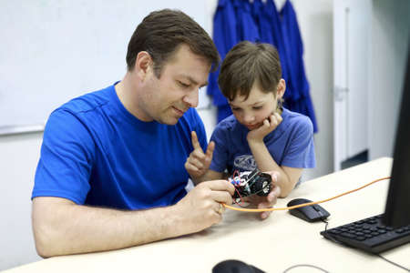 Father with his son programming robot at table in workshopの写真素材