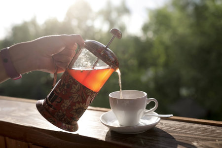 Person pouring tea from french press in a cafeの写真素材