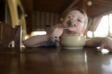 Child eating vareniki at table in cafeの写真素材