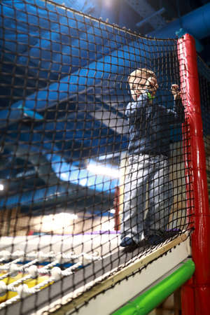 Child holding on to rope mesh at playground