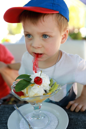 Child eating dessert at table in cafeの写真素材
