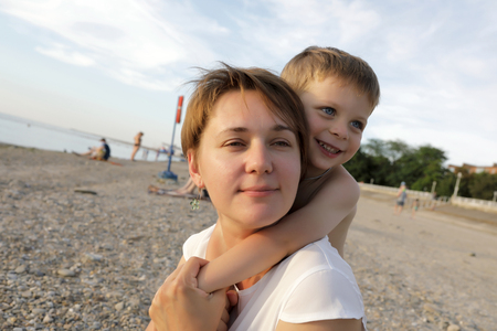 Son hugging his mother on the beachの写真素材