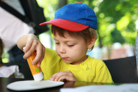 Boy glues piece of paper at table