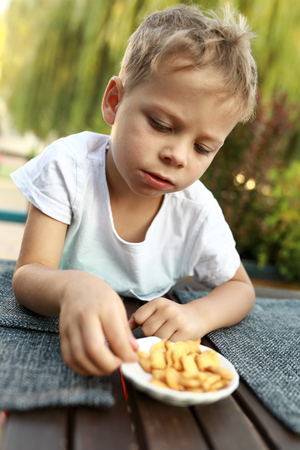 Child eating crackers at table in cafeの写真素材