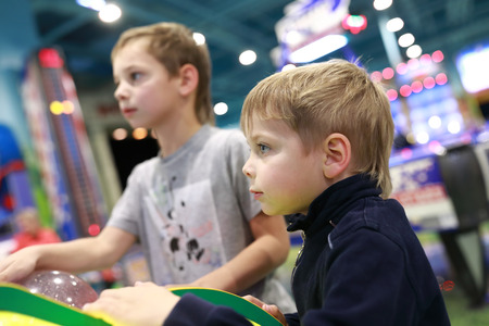 Children playing arcade game in amusement parkの写真素材