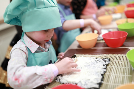 Child putting sushi ingredients on nori with riceの写真素材