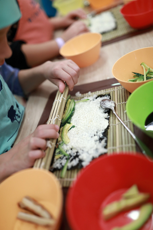 Person is rolling mat over sushi at cooking classの写真素材