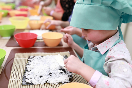 Child is making sushi at cooking classの写真素材