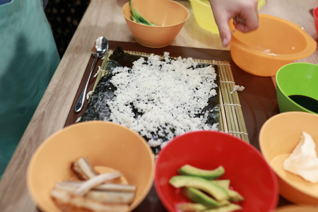 Rice on nori and plates of sushi fillingの写真素材