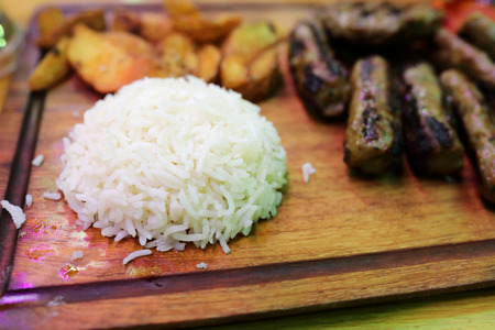 Rice and kebabs on wooden board in restaurantの写真素材