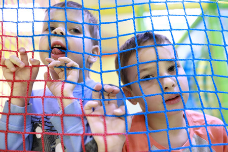 Portrait of two pensive children in toy cageの写真素材