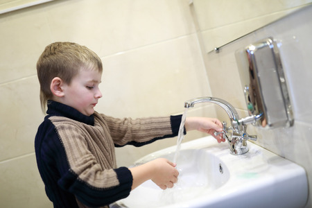 Boy washing his hands in the sinkの写真素材