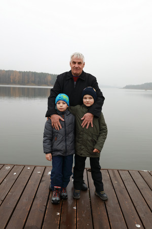 Grandfather with his grandsons posing on pier, Zaslavsky reservoir, Minsk region