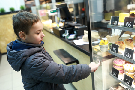 Child is choosing donat in a cafeの写真素材