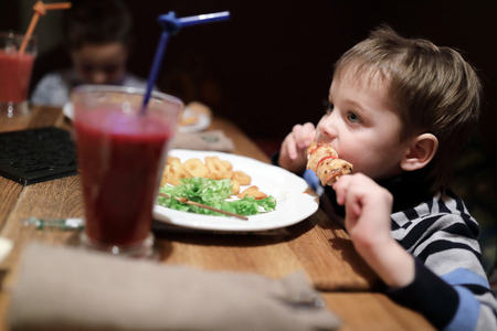 Child has kebab on skewer in restaurantの写真素材